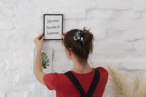 woman hanging a sign saying 'home sweet home'
